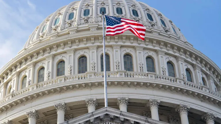 The U.S. flag flying in front of the U.S. Capitol.